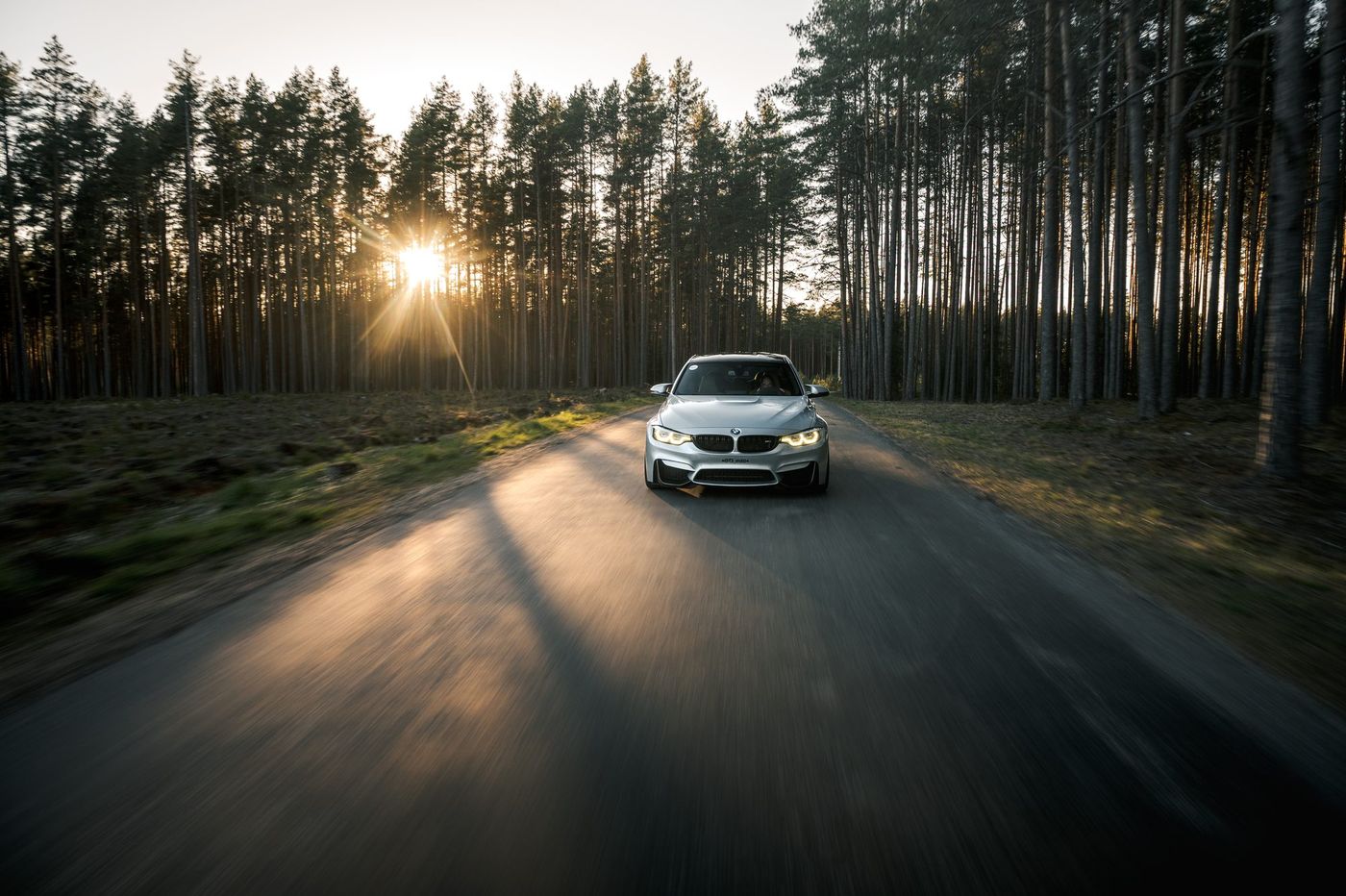 Silver BMW M3 (F80) on a forest road at sunset