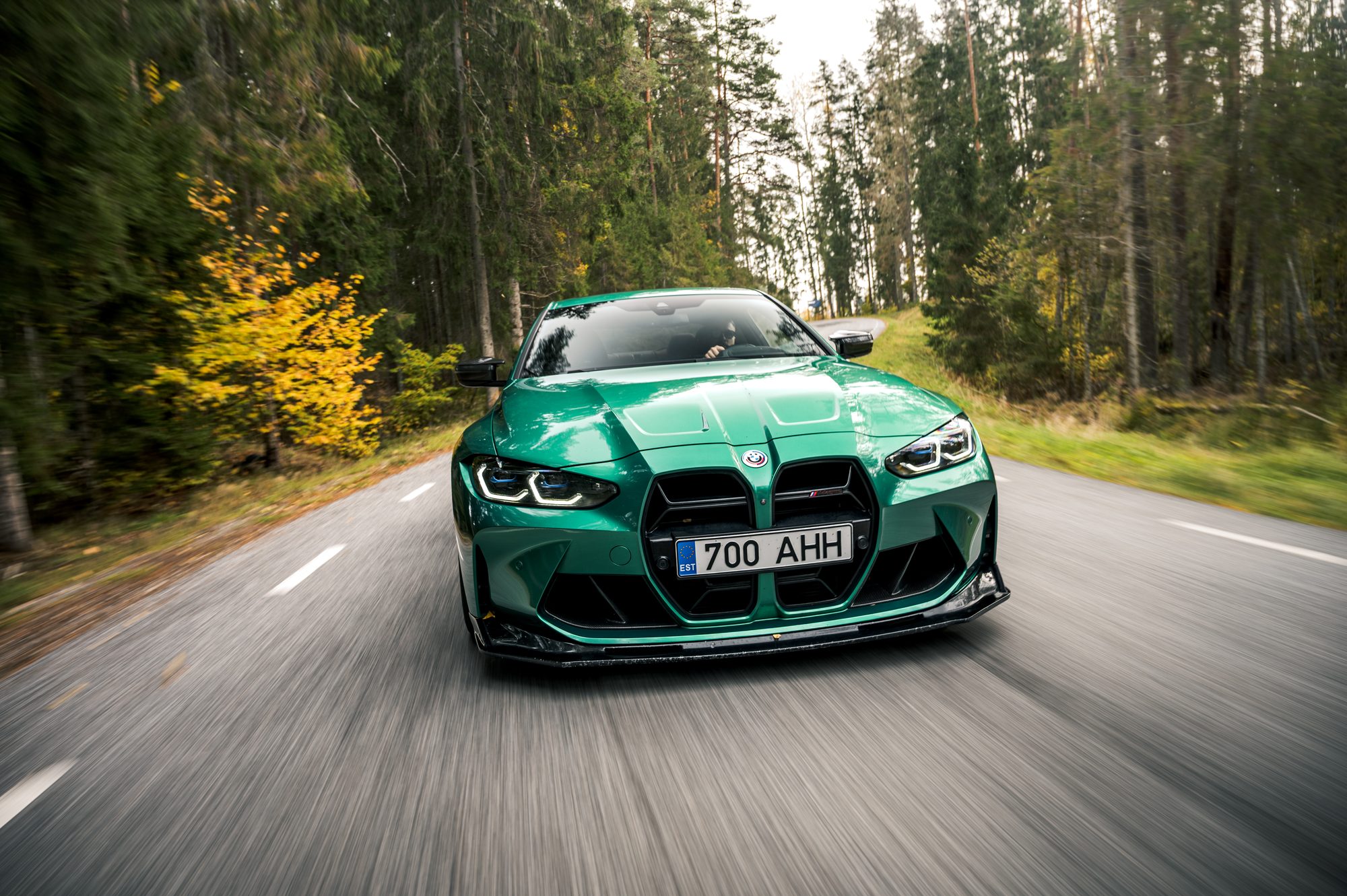 Green BMW M4 rolling shot on an autumn forest road