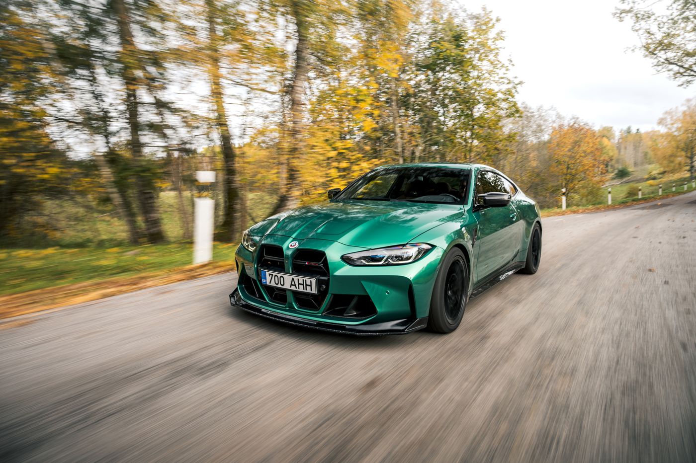 Green BMW M4 rolling shot on an autumn road